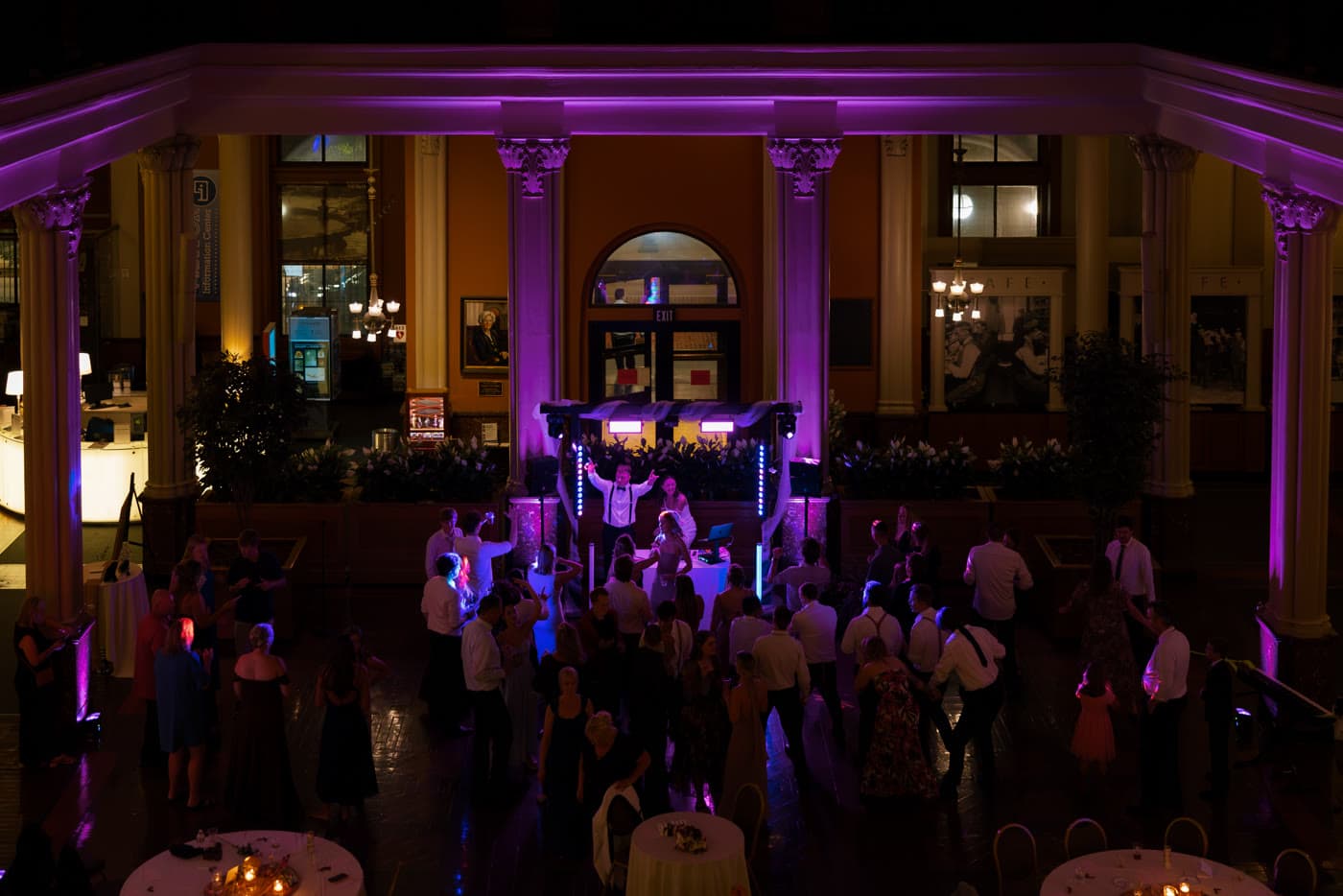 Packed dance floor under magenta column lighting in a classical venue