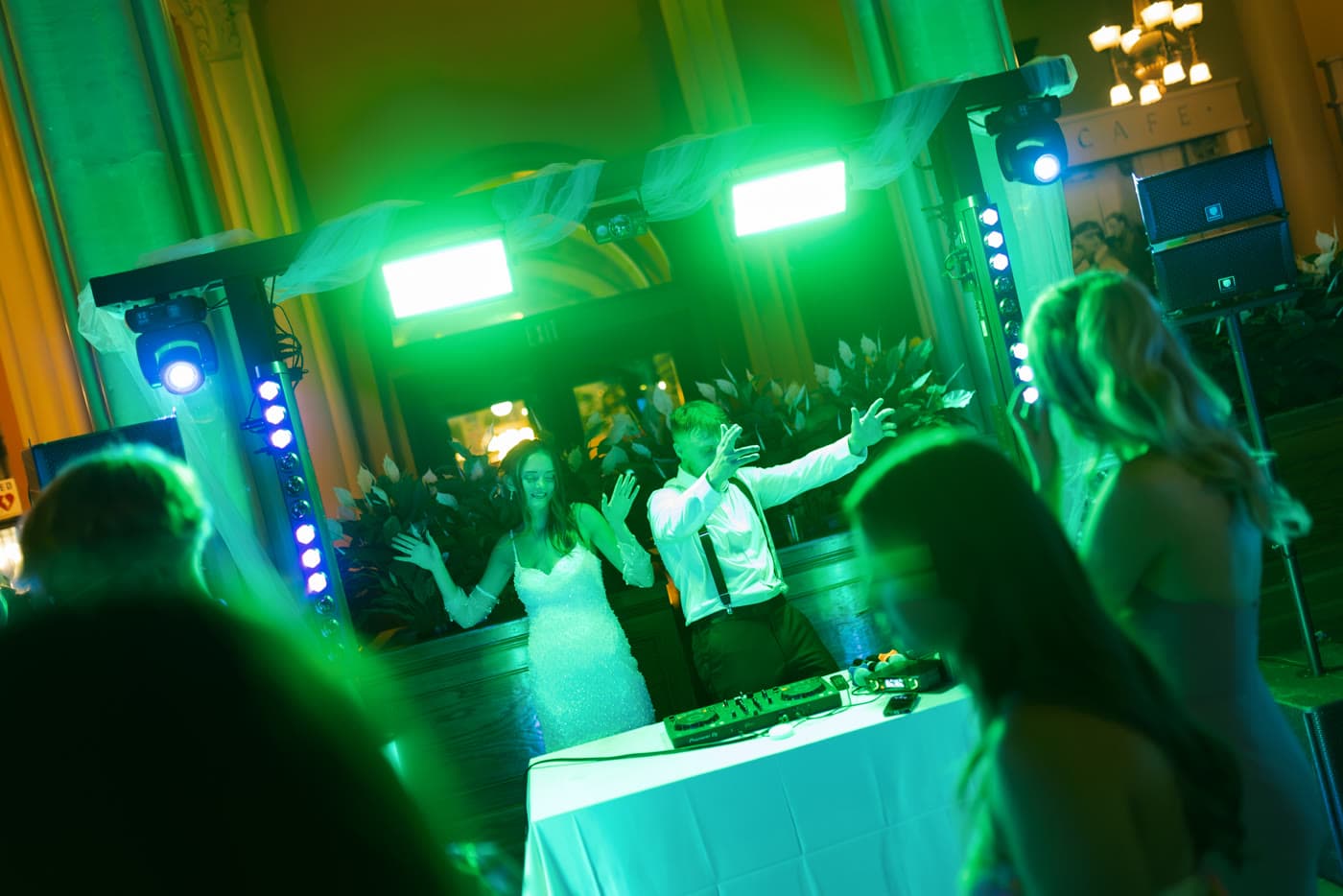 Couple dancing behind the DJ setup under green production lights